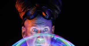 Portrait poétique de The Cosmic Joker derrière une grande bulle irisée et lumineuse.